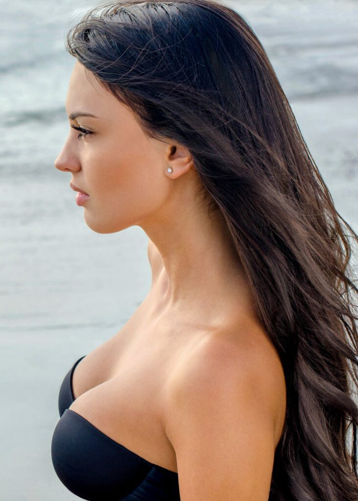 Side view of woman on beach with hair blowing in wind