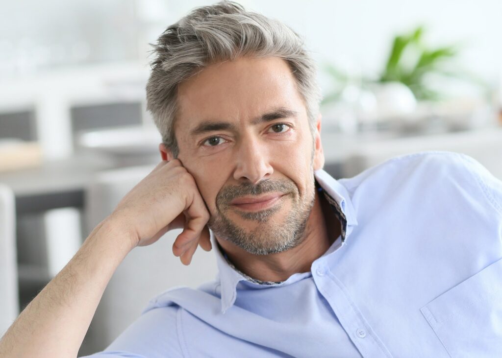 Handsome men in his 50s, with gray hair but looking young with no sagging skin and wrinkles after men facelift procedure